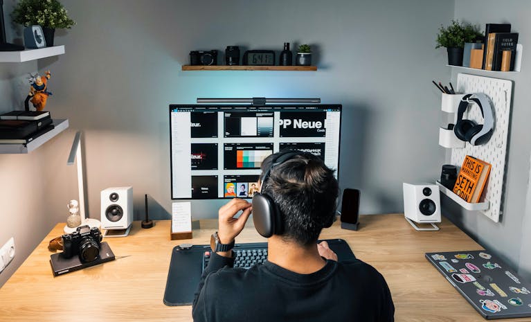 Cozy and organized home office workspace featuring a desktop computer, headphones, and creative decor.